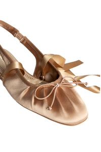 Detalle frontal de bailarinas de raso bronce con cintas y punta redondeada, diseño sofisticado