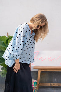 Blusa azul con lunares negros y mangas abullonadas, detalle lateral del diseño ligero y casual