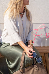 Blusa beige con escote pico combinada con falda satinada verde y bolso de ante marrón, estilo natural de AnnFou