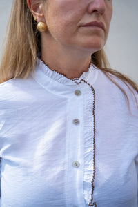 Detalle de la blusa blanca con cuello mao fruncido, volante central y ribete marrón en contraste, estilo femenino AnnFou