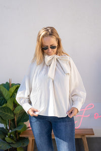 Blusa blanca con lazo grande en el cuello y mangas abullonadas, vista frontal completa combinada con vaqueros AnnFou