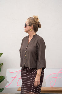 Blusa marrón chocolate de manga tres cuartos con botones frontales, combinada con falda satinada a lunares en look lateral
