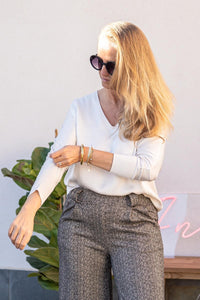 Mujer con blusa de raso blanca ajustando la manga, look elegante y natural con prenda de Ann Fou