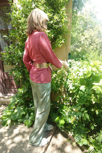 Vista trasera de la blusa tipo chaqueta granate con cinturón dorado, diseño cruzado y elegante