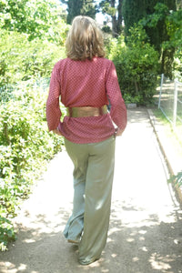 Blusa tipo chaqueta granate vista trasera, cinturón dorado y diseño cruzado fluido y elegante