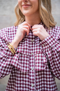 Detalle del cuello abotonado de la blusa vichy burdeos con volantes, tejido ligero y elegante