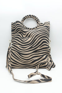 Vista frontal del bolso de piel con estampado cebra, diseño estructurado con asa circular, estilo animal print AnnFou