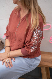 Chaqueta bomber color teja con mangas decoradas con lentejuelas, estilo relajado y look sentada