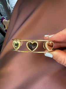 Brazalete dorado de acero inoxidable con tres corazones calados, acabado brillante y diseño elegante