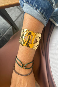 Brazalete ancho dorado de acero inoxidable con diseño entrelazado, acabado brillante y estilo sofisticado