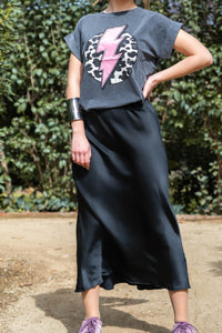 Brazalete plateado modelo jirafa combinado con camiseta gráfica y falda satinada negra, look urbano con actitud