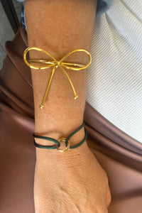 Brazalete dorado de acero inoxidable con diseño de lazo abierto, estilo femenino y minimalista, lucido en la muñeca