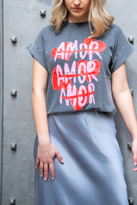 Detalle de la camiseta gris con palabra AMOR repetida sobre corazones, estilo urbano con mensaje positivo