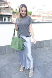 Camiseta joya gris con abalorios combinada con falda satinada plateada y bolso verde, look urbano elegante