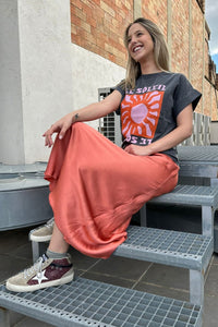 Camiseta gris Le Soleil con estampado gráfico de sol en tonos coral y rosa, estilo urbano desenfadado
