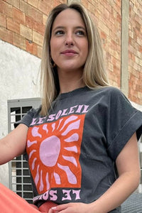 Camiseta gris Le Soleil con estampado gráfico de sol en tonos coral y rosa vista desde ángulo superior

