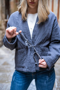 Detalle del lazo ajustable en chaqueta gris de algodón acolchado, ideal para entretiempo