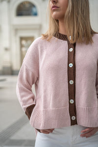 Detalle de chaqueta rosa palo con contraste en marrón chocolate y tejido acanalado