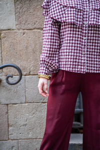 Cuff metálico dorado tipo esclava combinado con camisa de cuadros y pantalón satinado, look casual y sofisticado