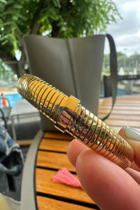 Esclava dorada de acero inoxidable con diseño espiral flexible, detalle en primer plano con acabado brillante