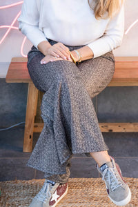 Pantalón ancho texturizado en look casual, mostrado con piernas cruzadas para destacar la caída del tejido
