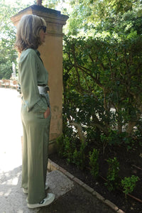 Vista lateral de pantalón satinado verde con caída fluida, estilo relajado y elegante