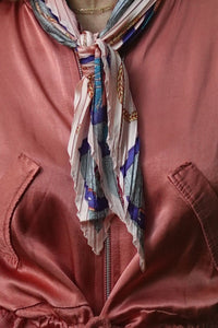 Pañuelo plisado rosado con detalles en azul y cadenas doradas, anudado al cuello con estilo elegante de AnnFou