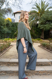 Vista lateral del poncho verde en lurex combinado con pantalón fluido gris