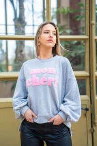 Sudadera Mon Chéri gris oscuro con letras rosas en relieve, detalle del diseño y textura del tejido