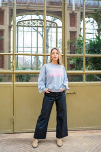 Sudadera Mon Chéri gris oscuro con letras rosas, combinada con pantalón ancho efecto piel y botines beige